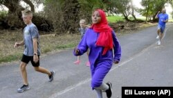 Ubah Yusuf, center, runs with volunteers in the Athletics United program in Logan, Utah. (Eli Lucero/The Herald Journal via AP)