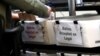 FILE - A Miami-Dade County Elections Department employee places a vote-by-mail ballot for the August 18 primary election into a box for rejected ballots at the Miami-Dade County Elections Department, in Doral, Florida, July 30, 2020.
