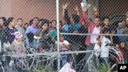 In this March 27, 2019, file photo, Central American migrants wait for food in a pen erected by U.S. Customs and Border Protection to process a surge of migrant families and unaccompanied minors in El Paso, Texas. 